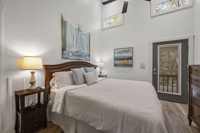 bedroom with light wood-type flooring and a towering ceiling