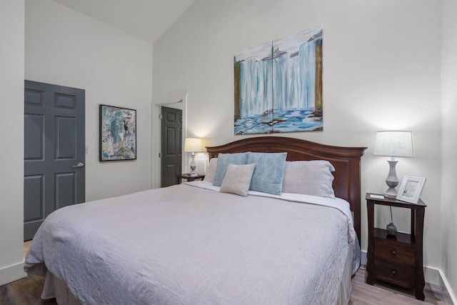 bedroom featuring wood-type flooring and high vaulted ceiling