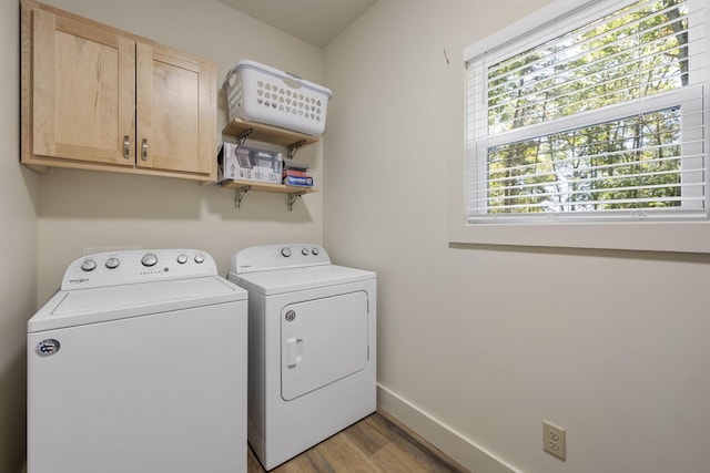 washroom with cabinets, light wood-type flooring, and washing machine and clothes dryer