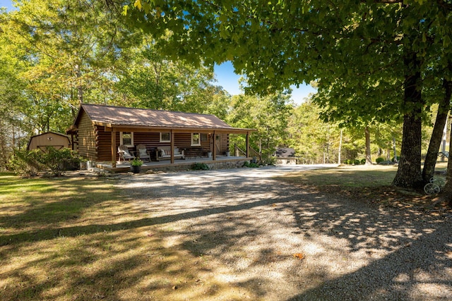 back of house featuring covered porch, a yard, and log exterior