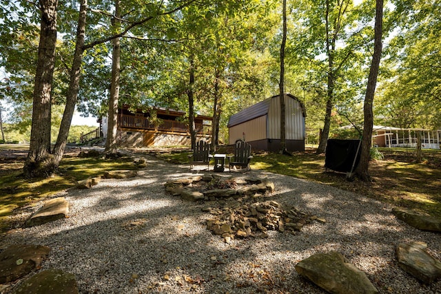 view of yard with an outdoor structure, a deck, and a storage shed