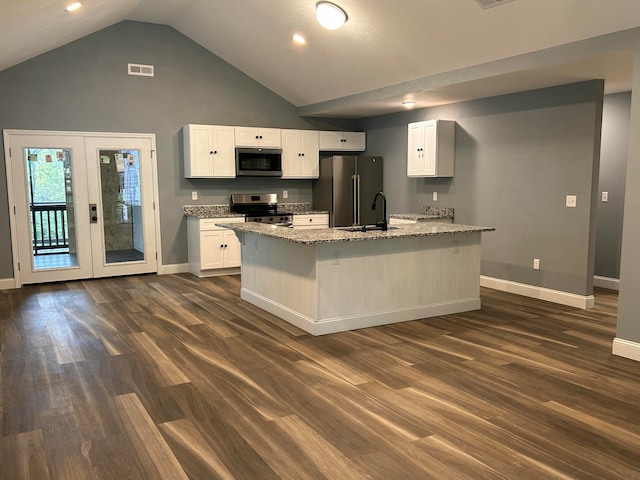 kitchen featuring dark wood-type flooring, a center island with sink, white cabinets, light stone counters, and stainless steel appliances