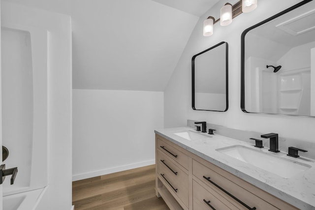 bathroom featuring hardwood / wood-style flooring, vanity, lofted ceiling, and walk in shower