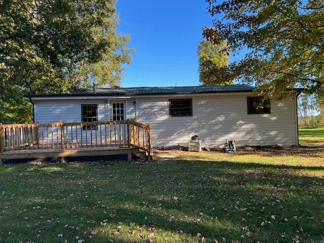 rear view of house featuring a wooden deck and a lawn