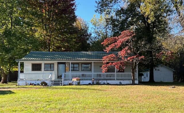 view of front facade featuring a porch, a front lawn, and an outbuilding