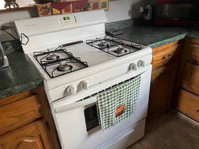 kitchen featuring white range with gas cooktop and dark tile patterned flooring