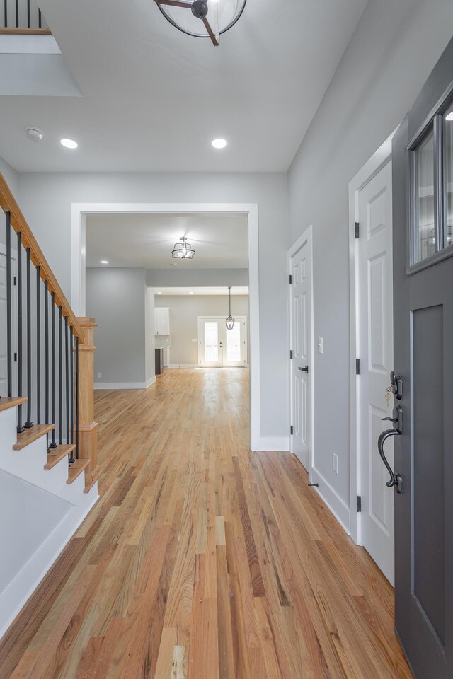 foyer entrance with light wood-type flooring, recessed lighting, stairs, and baseboards