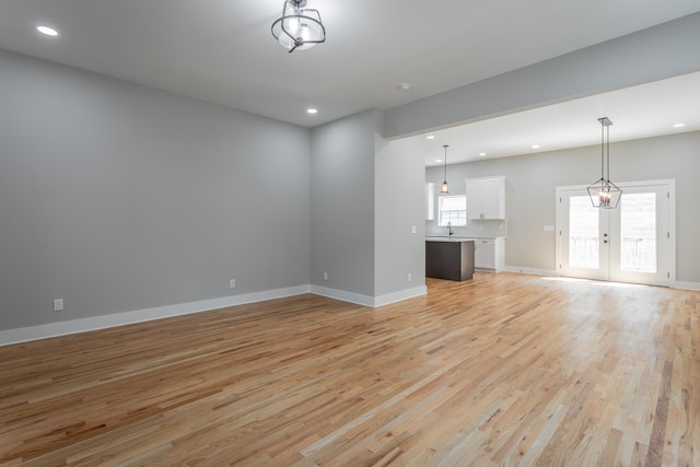 unfurnished living room featuring french doors, light hardwood / wood-style floors, and sink