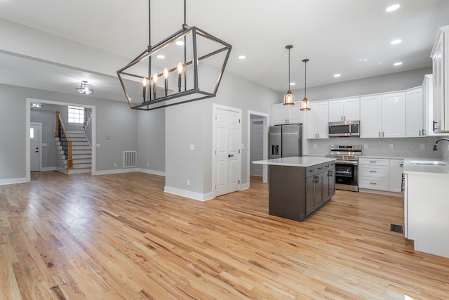 kitchen featuring a center island, sink, hanging light fixtures, white cabinetry, and stainless steel appliances