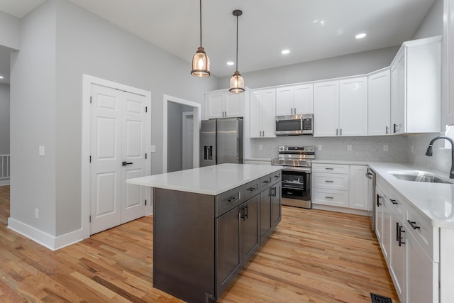 kitchen with a sink, light countertops, stainless steel appliances, and light wood-style flooring