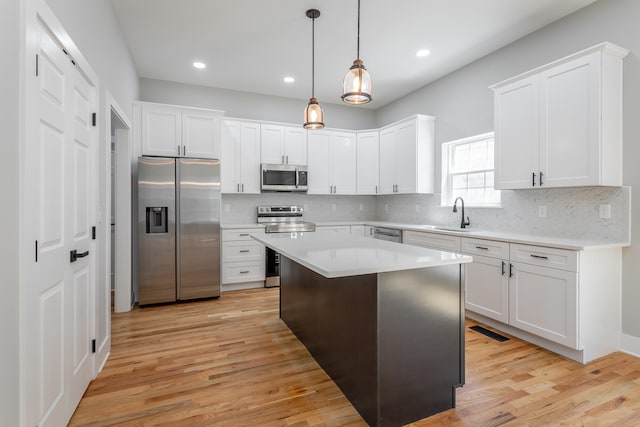 kitchen with white cabinets, pendant lighting, a center island, and stainless steel appliances