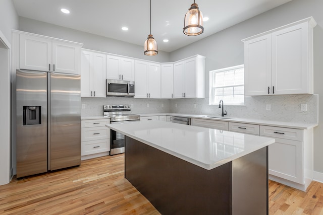 kitchen with sink, white cabinets, decorative light fixtures, and appliances with stainless steel finishes