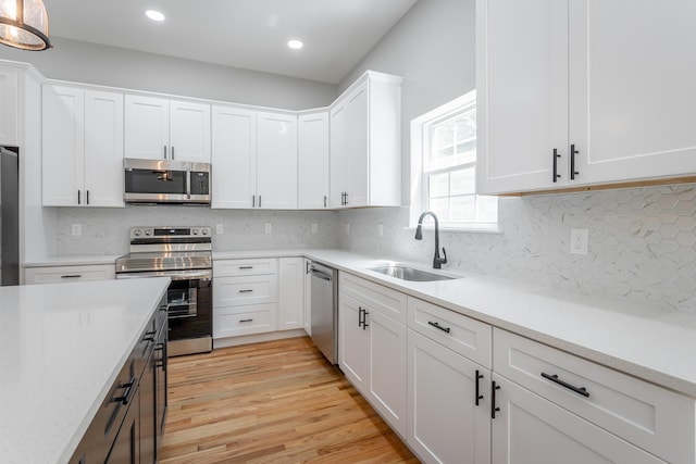 kitchen featuring light countertops, white cabinets, appliances with stainless steel finishes, and a sink