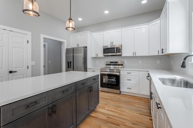 kitchen featuring pendant lighting, appliances with stainless steel finishes, a sink, recessed lighting, and white cabinetry