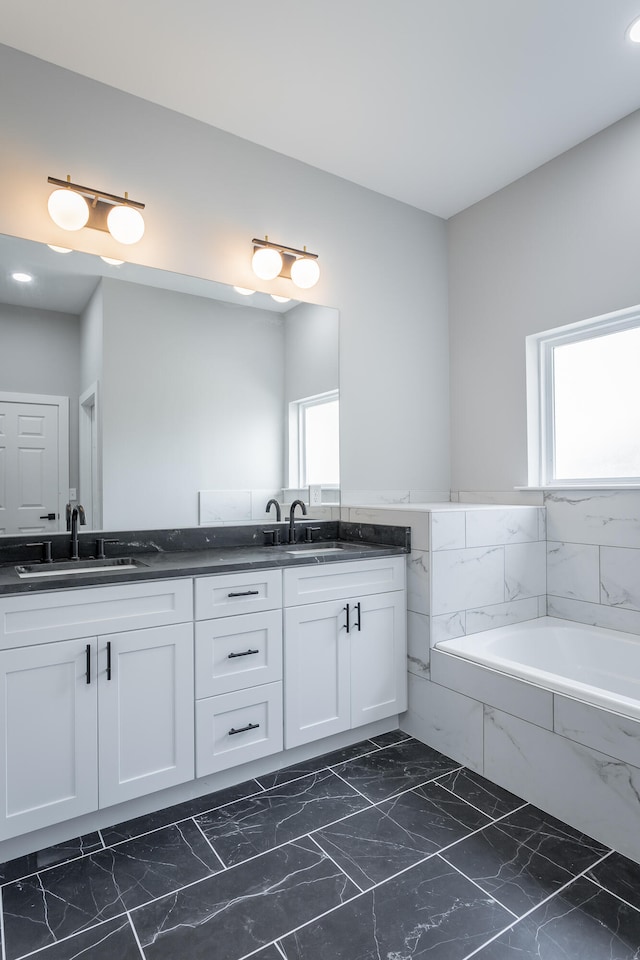 bathroom featuring tiled tub and vanity