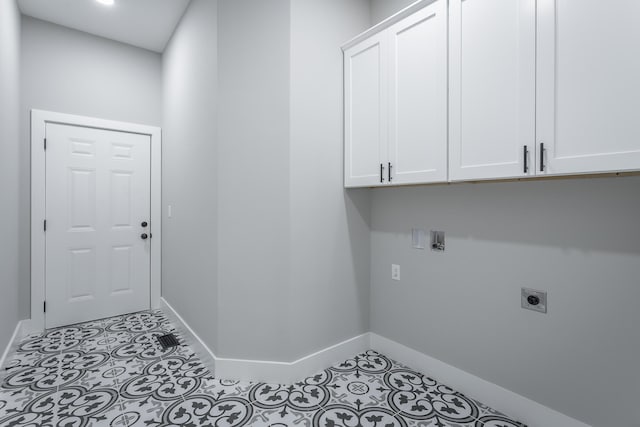 laundry area with hookup for an electric dryer, cabinets, and light tile patterned flooring