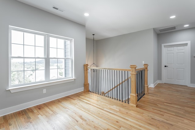 corridor with visible vents, baseboards, wood finished floors, and an upstairs landing