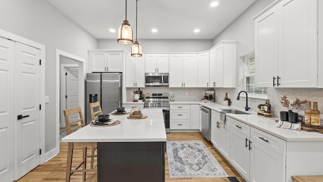 kitchen with a kitchen breakfast bar, a center island, a sink, light wood-style flooring, and stainless steel appliances