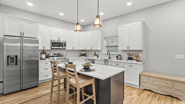 kitchen with decorative light fixtures, white cabinetry, backsplash, a center island, and stainless steel appliances