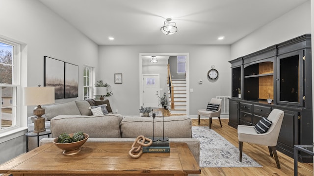 living area with stairs, recessed lighting, and light wood-style flooring