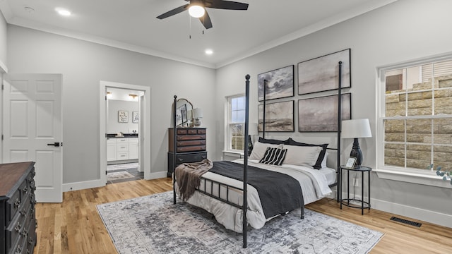 bedroom featuring crown molding, baseboards, light wood finished floors, and visible vents