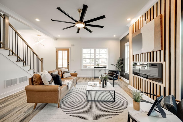 living room with ornamental molding, light hardwood / wood-style floors, and ceiling fan