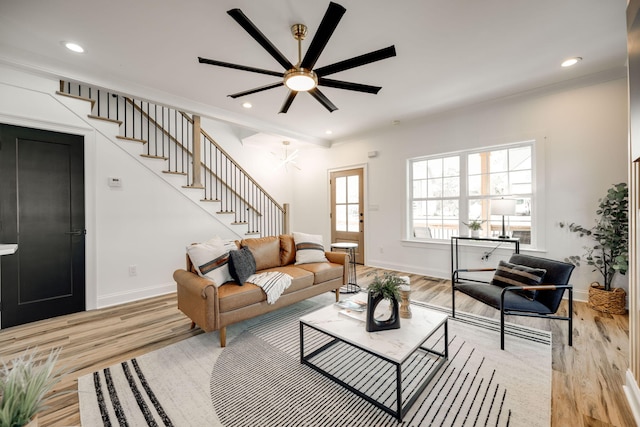 living room featuring light hardwood / wood-style flooring, ceiling fan, and crown molding