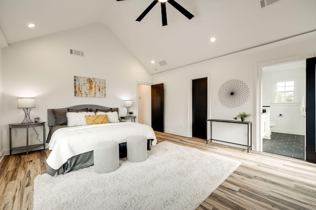 bedroom with light wood-type flooring, ceiling fan, high vaulted ceiling, and connected bathroom