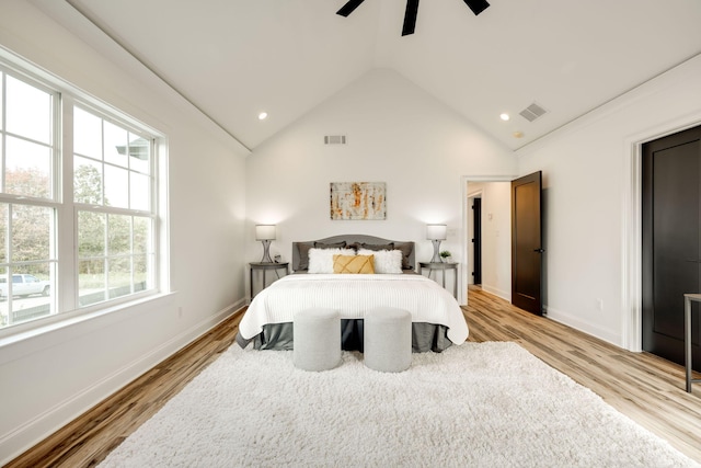 bedroom featuring multiple windows, ceiling fan, light wood-type flooring, and high vaulted ceiling