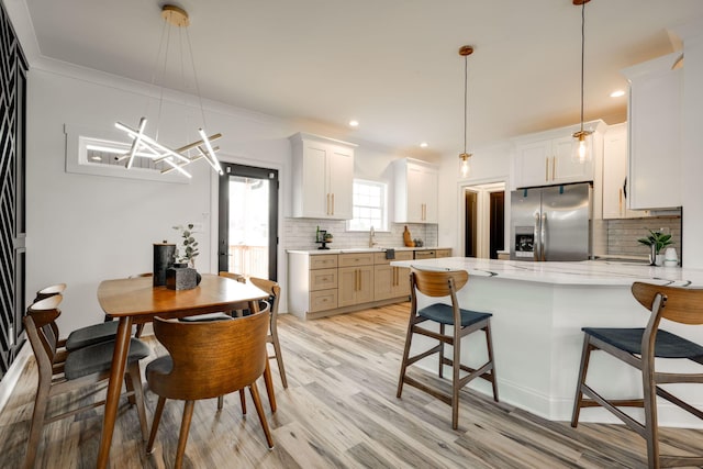 kitchen featuring stainless steel fridge, white cabinetry, pendant lighting, decorative backsplash, and light hardwood / wood-style floors