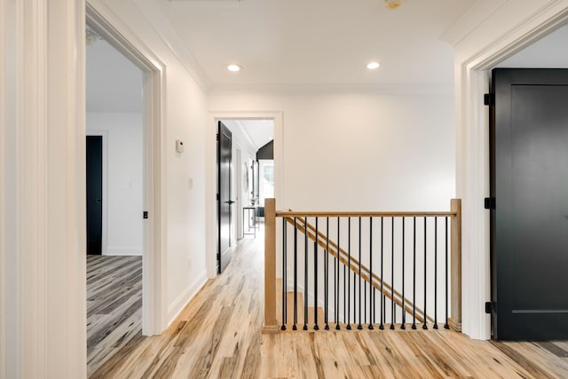 corridor featuring light wood-type flooring and ornamental molding