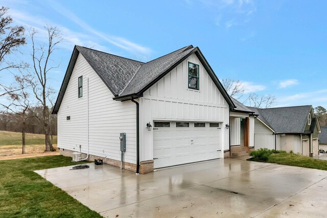 exterior space featuring a garage, a shingled roof, concrete driveway, a front lawn, and board and batten siding