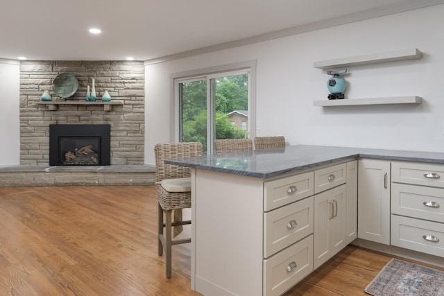 4011 Patton Edwards Dr, Chattanooga, TN 37412 - kitchen featuring a breakfast bar, dark stone countertops, light wood-style floors, a fireplace, and open floor plan