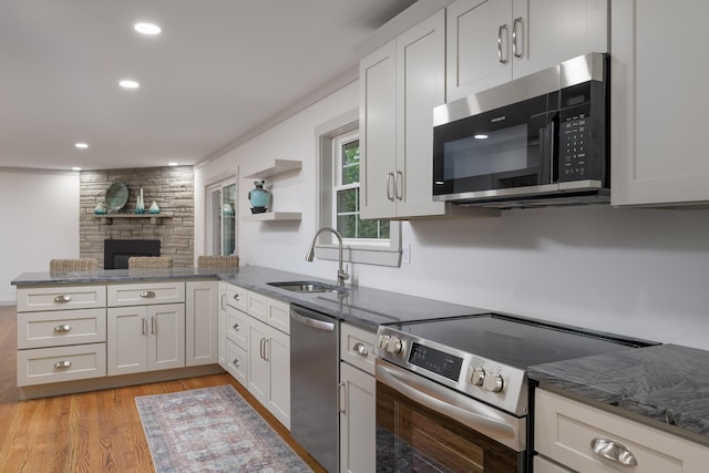 4011 Patton Edwards Dr, Chattanooga, TN 37412 - kitchen with appliances with stainless steel finishes, a peninsula, dark stone counters, light wood finished floors, and white cabinets
