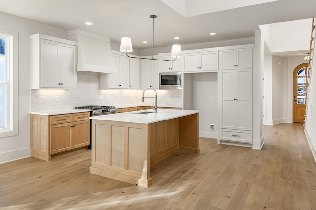 kitchen with light hardwood / wood-style flooring, white cabinets, a kitchen island with sink, and stainless steel appliances