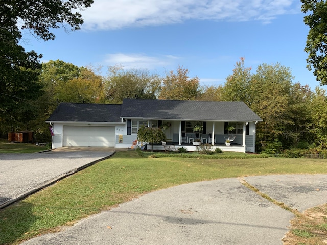 ranch-style house featuring covered porch, a front yard, and a garage