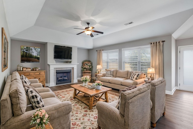 living room featuring hardwood / wood-style floors, ceiling fan, vaulted ceiling, and a tile fireplace