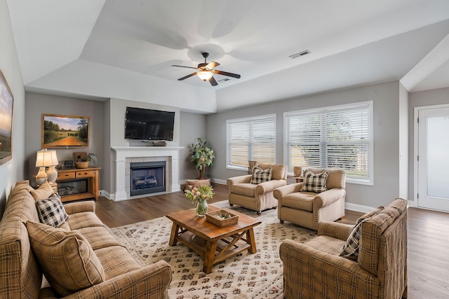 living room featuring a fireplace, ceiling fan, light hardwood / wood-style flooring, and lofted ceiling