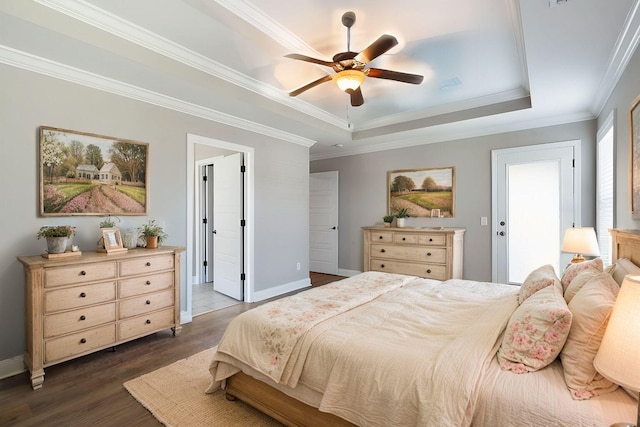 bedroom featuring dark hardwood / wood-style flooring, ornamental molding, a tray ceiling, and ceiling fan