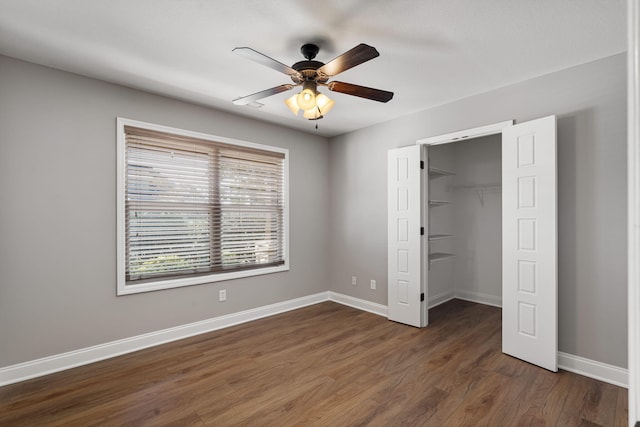 unfurnished bedroom featuring a closet, a spacious closet, ceiling fan, and dark hardwood / wood-style floors