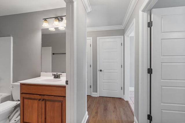 bathroom with toilet, vanity, hardwood / wood-style flooring, and crown molding