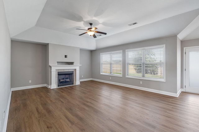 unfurnished living room with a tiled fireplace, wood-type flooring, and ceiling fan