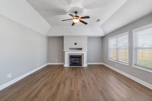 unfurnished living room with dark hardwood / wood-style flooring, a tiled fireplace, lofted ceiling, and ceiling fan