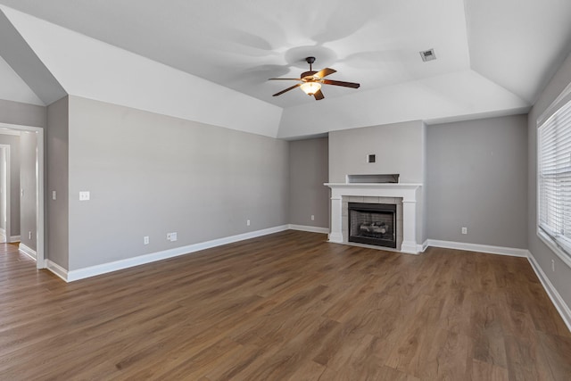 unfurnished living room featuring a tiled fireplace, dark hardwood / wood-style flooring, ceiling fan, and vaulted ceiling