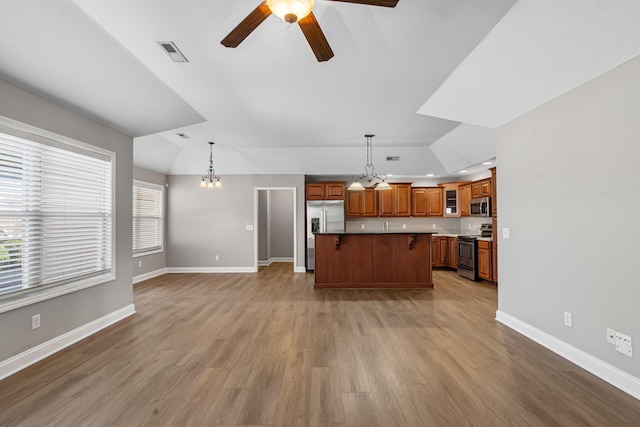 kitchen featuring light wood-type flooring, stainless steel appliances, hanging light fixtures, and a kitchen island