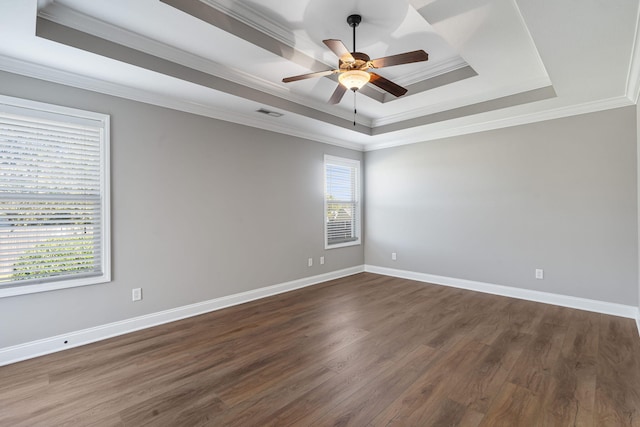 empty room featuring dark wood-type flooring, ceiling fan, a raised ceiling, and ornamental molding