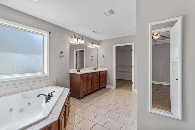 bathroom featuring a relaxing tiled tub, ceiling fan, vanity, and tile patterned flooring