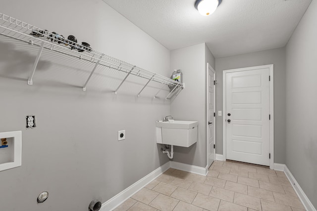 clothes washing area featuring sink, hookup for a washing machine, a textured ceiling, and hookup for an electric dryer