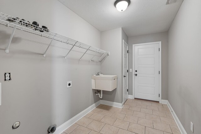 laundry room with a textured ceiling and sink