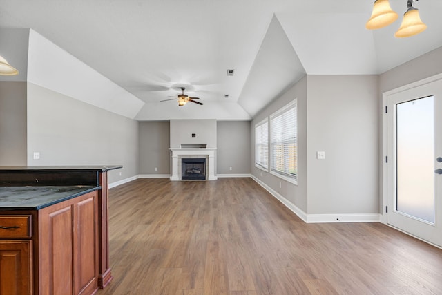 unfurnished living room featuring ceiling fan, lofted ceiling, light hardwood / wood-style floors, and a fireplace